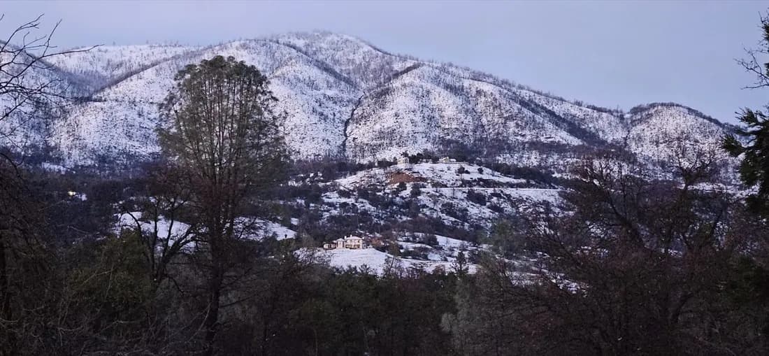 Snow-dusted Sierra foothills above a river canyon.