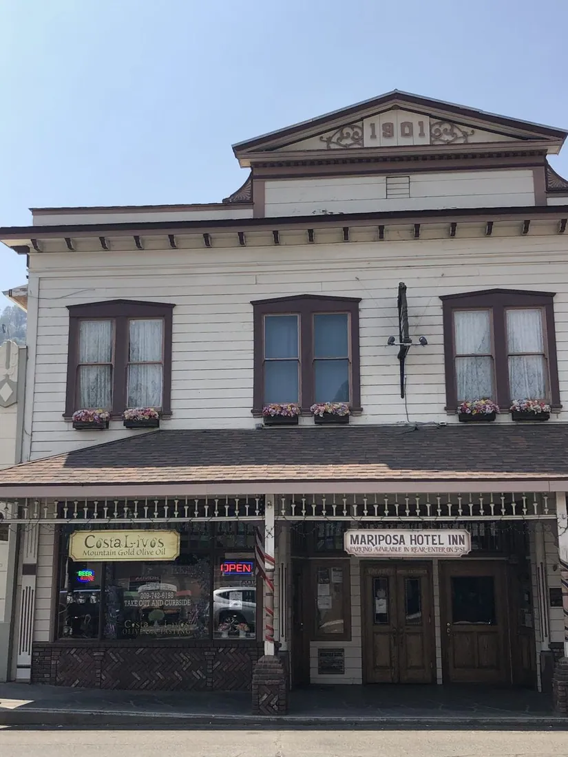Two-story historic hotel facade with a covered balcony over the sidewalk.